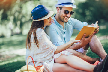 Beautiful couple enjoying picnic time outdoor reading book