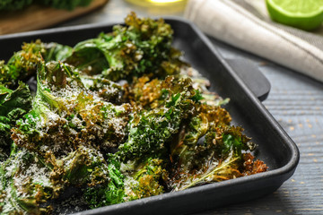 Tasty baked kale chips on grey table, closeup