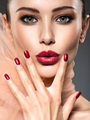 closeup face of a fashion woman with stylish makeup, red nails and lips