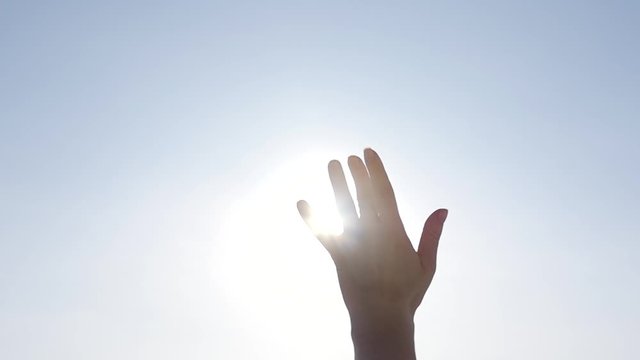 Girl looks at the sun through her hand