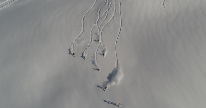Aerial slow motion: five skiers and one snowboarder ride the first freeride line. off-piste skiing, Heli skiing. freeriders roll out large untouched snow valleys. Freeride ski & Epic free ride scene