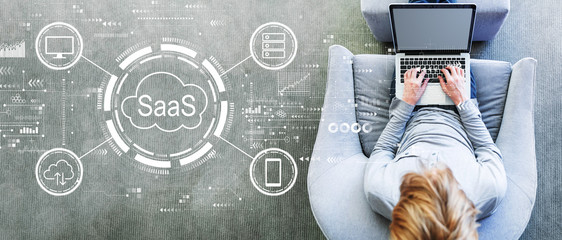 SaaS - software as a service concept with man using a laptop in a modern gray chair