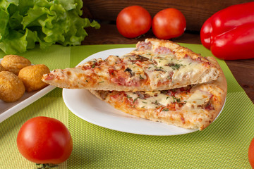 Pizza assorted slices with nuggets on a green napkin. Still-life. Wooden table. Greens and vegetables.