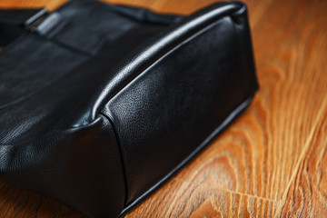 Black notebook peeking out of the pocket of a black leather bag close-up, macro Handmade, natural materials.