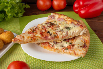 Pizza assorted slices with nuggets on a green napkin. Still-life. Wooden table. Greens and vegetables.
