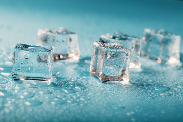 Ice cubes are scattered with water drops scattered on a blue background.