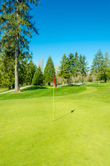 Obraz premium Golf course with gorgeous green and pond.