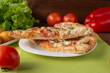 Pizza assorted slices with nuggets on a green napkin. Still-life. Wooden table. Greens and vegetables.