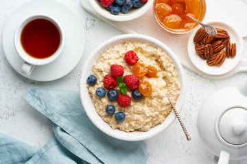 Oatmeal porridge with blueberry, raspberries, jam and nuts, top view. Breakfast with berries