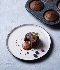 fresh hot vegan chocolate fondant lava with  berries   on a white plate on a blue-gray background