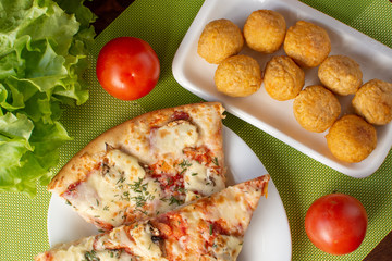 Pizza assorted slices with nuggets on a green napkin. Still-life. Wooden table. Greens and vegetables.