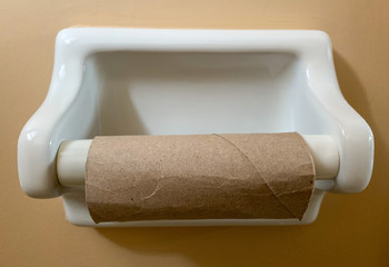Empty roll of toilet paper in a white porcelain holder on a bathroom wall.