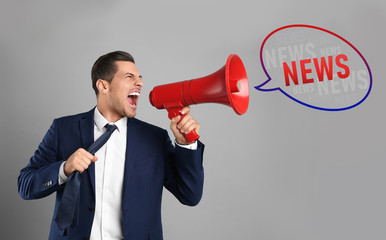Handsome man with megaphone on grey background