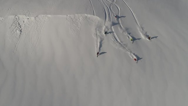 Aerial slow motion: five skiers and one snowboarder ride the first freeride line. off-piste skiing, Heli skiing. freeriders roll out large untouched snow valleys. Freeride ski & Epic free ride scene