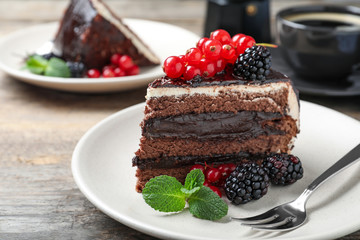 Fototapeta na wymiar Tasty chocolate cake with berries on wooden table, closeup