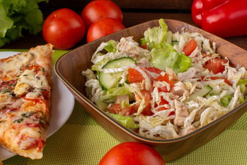 Pizza assorted slices with a salad of fresh vegetables on a green napkin. Still-life. Wooden table. Greens and vegetables.