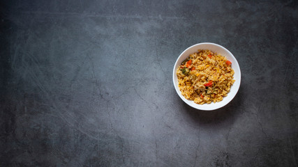 Large white deep bowl with pilaf. Rice with vegetables. National cuisine. dark background. Top view with place for text.