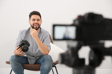 Young blogger with camera recording video indoors