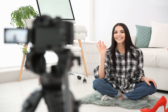 Young blogger recording video on camera indoors