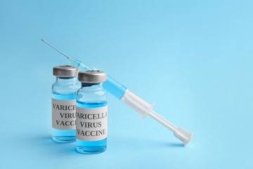 Chickenpox vaccine and syringe on light blue background. Varicella virus prevention