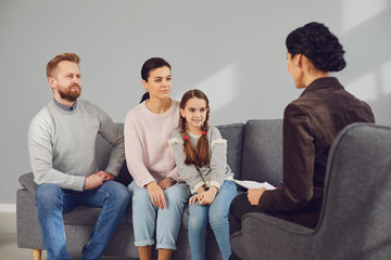 Family psychologist. Female psychologist at a psychotherapy session with family in the office. - obrazy, fototapety, plakaty