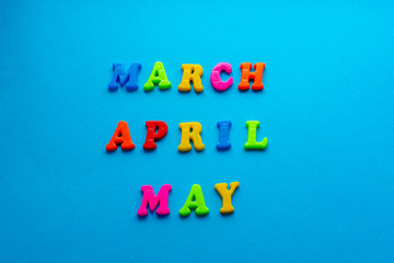 words "March, April, May" from colored plastic magnets on blue paper background