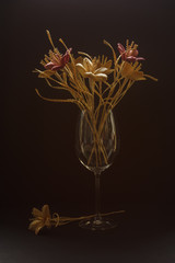 A glass vase with a bouquet of flowers made from straw on a dark background