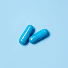 Two blue capsules. Pills for men's health and sexual energy on an isolated background. Concept of erection, potency. Treatment of male infertility and impotence. Copy space