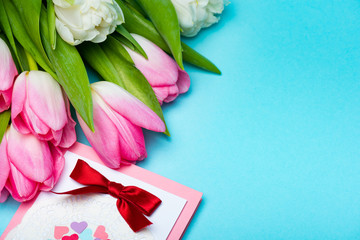 Close up view of bouquet of tulips near greeting card on blue surface
