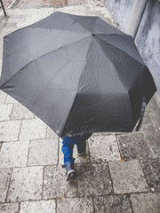 Toned funny image of little boys feet showing from under the big umbrella