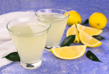 Refreshing lemonade and fresh lemons on a light blue background.Close-up.