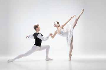 Balance. Graceful classic ballet dancers dancing isolated on white studio background. Couple in tender clothes like a white swan characters. The grace, artist, movement, action and motion concept.