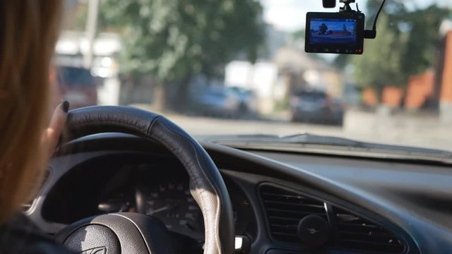 Beautiful girl hands on the steering wheel of a car. View of car traffic at a crossroads through a car windshield