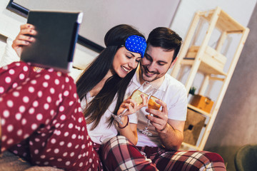 Happy young couple lying on the bed in a bedroom and using digital tablet.