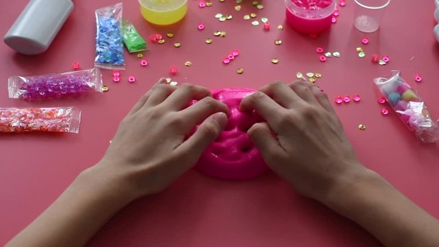 a girl making slime herself. child making slime on pink background.