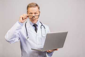 Portrait of senior Mature Doctor Using Laptop isolated over grey Background.