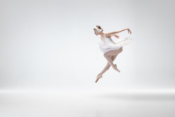Flying bird. Graceful classic ballerina dancing isolated on white studio background. Woman in tender clothes like a white swan characters. The grace, artist, movement, action and motion concept.