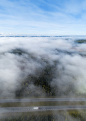 Aerial view of semi truck along empty country highway. Foggy summer morning. Vehicles shipping goods.