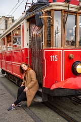 girl brown hair in coat sit running Board red tram