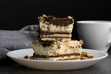 Homemade cake with nuts and chocolate cream in the background coffee shot on a plate dark background