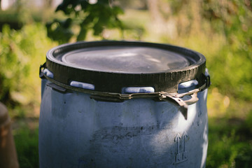 Close up of old plastic closed barrel with seal in the garden. Sealed water tank. Use for storage, collecting rain water, fertilizers, fruits