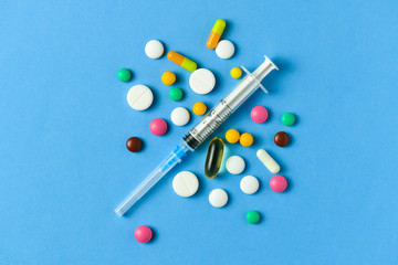 Pills, tablets, syringe, vitamins, drugs, medicine on blue background