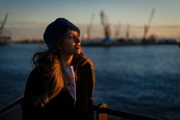 Middle eastern young female model in the beautiful port of hamburg during sunset.