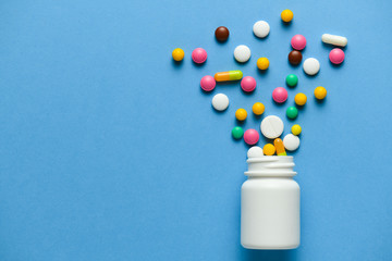 Assorted medicine pills, tablets, capsules blow out or ejection from bottle on blue background....