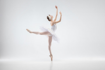 Obraz na płótnie Canvas Graceful classic ballerina dancing isolated on white studio background. Woman in tender clothes like a white swan characters. The grace, artist, movement, action and motion concept. Looks weightless.