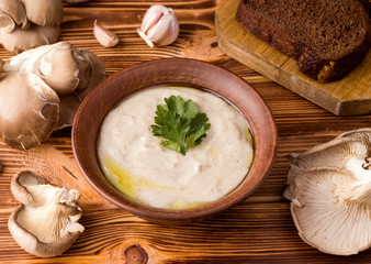 mushroom cream soup from oyster mushrooms next to fresh mushrooms on a wooden table.