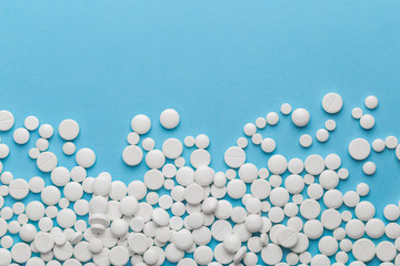 scattered white pills on a blue table. Layout for special offers such as advertising or other ideas. The concept of medicine, pharmacy and healthcare. Space for copy. flat lay for text or logo.