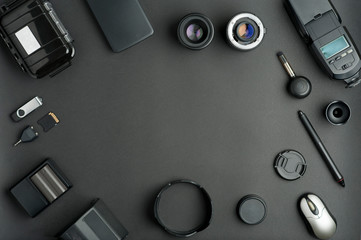 Flat assembly composition with photographic production equipment, with central writing space, on black background. Top view