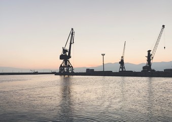 Obraz premium Silhouettes of the cranes in the sea port