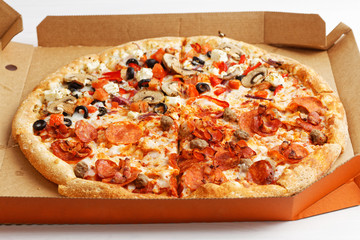 Half meat and half vegetable pizza on white wooden table. Angle view. Shallow focus.